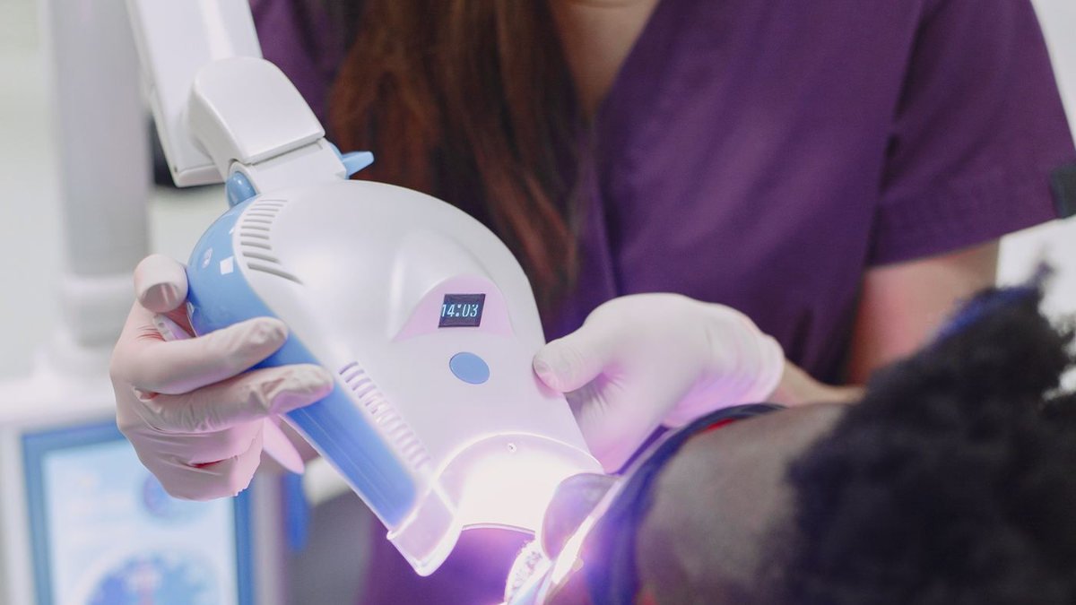 Aplicação de clareamento dental em consultório, com fotopolimerizador e barreira de proteção gengival