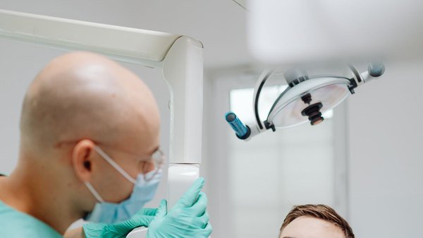 Cirurgião-dentista realizando exame radiográfico em paciente no consultório
