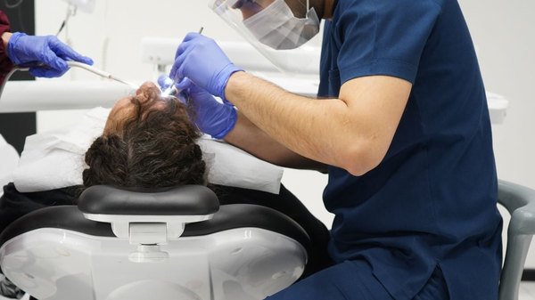 Cirurgião-dentista realizando procedimento em paciente na cadeira odontológica